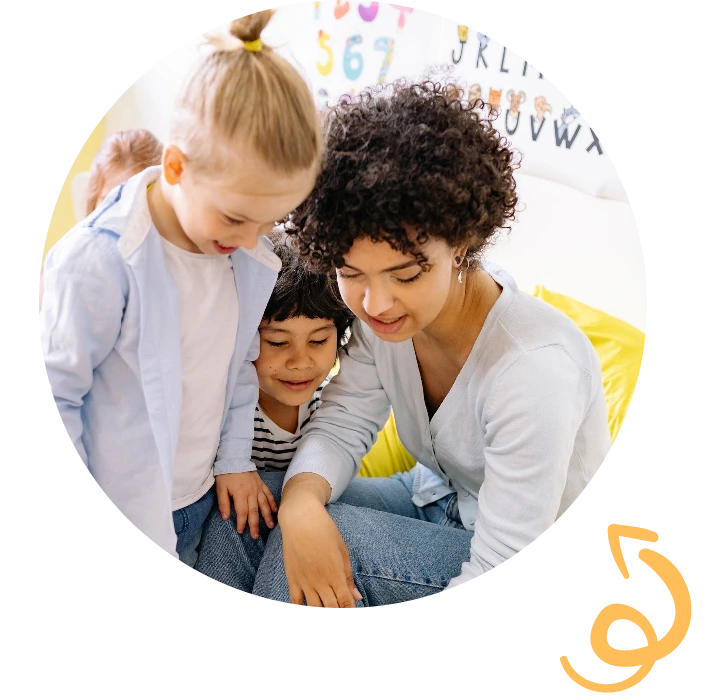 A therapist sitting on the floor playing and reading with two young children